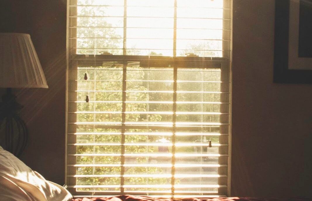Sunlight streaming through the bedroom window with closed blinds.