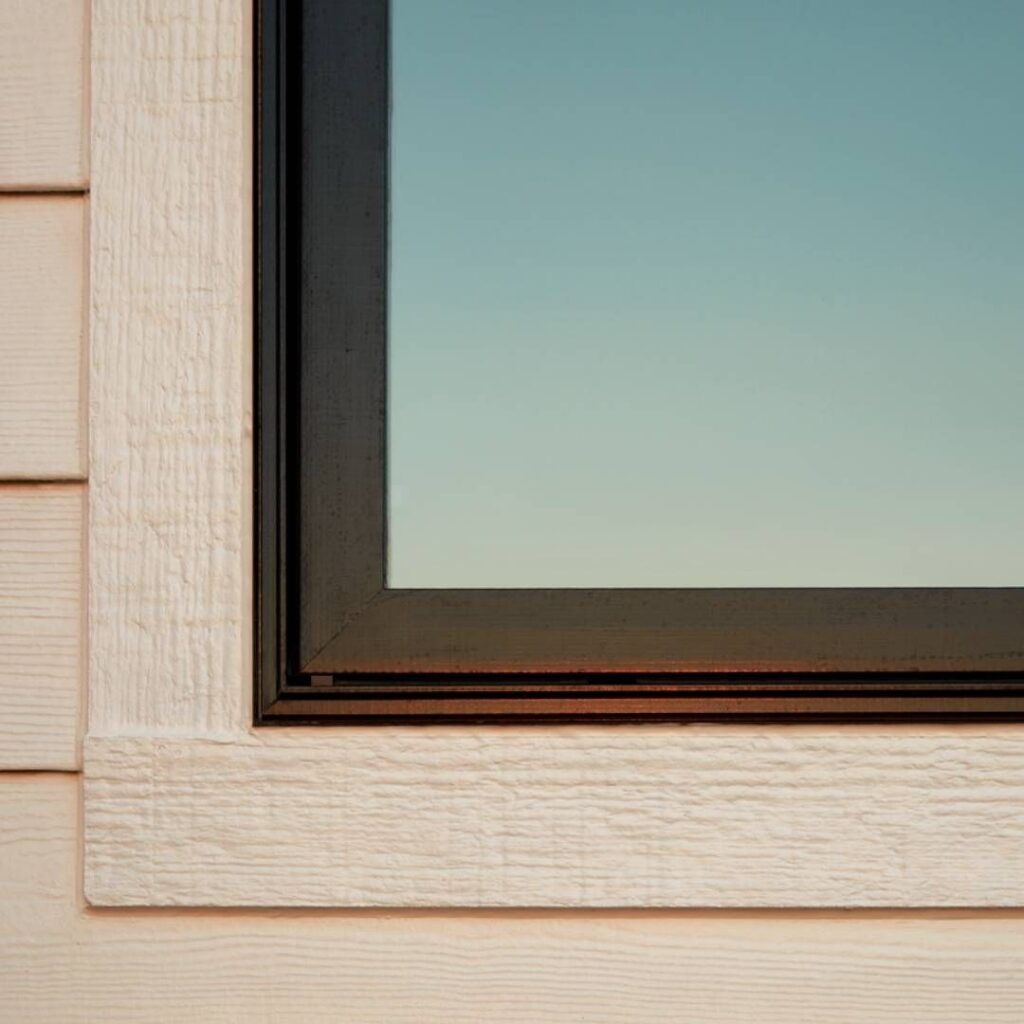 Exterior window corner with textured siding and clear glass.